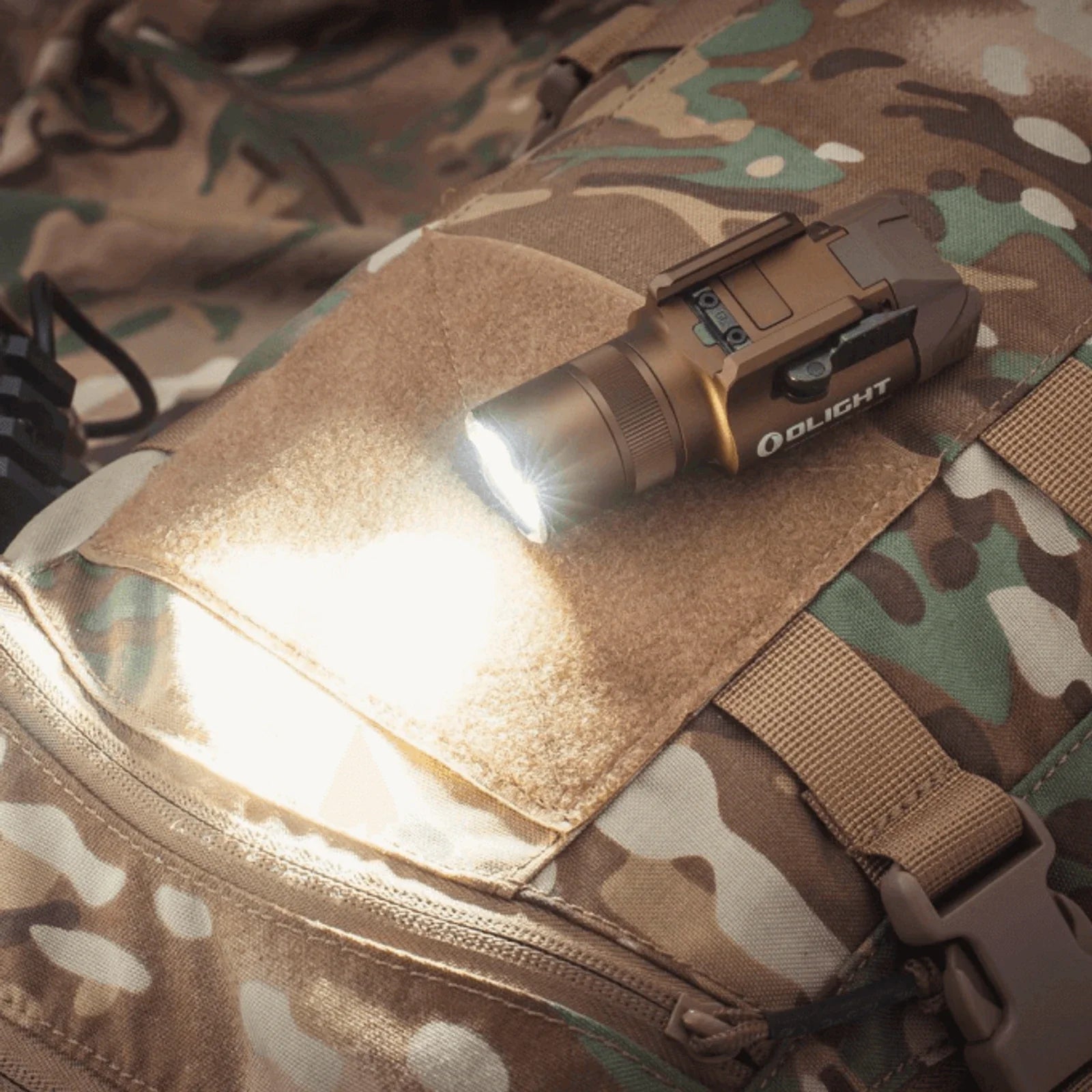 Olight Baldr Pro R Desert Tan projecting white light while mounted on tactical gear