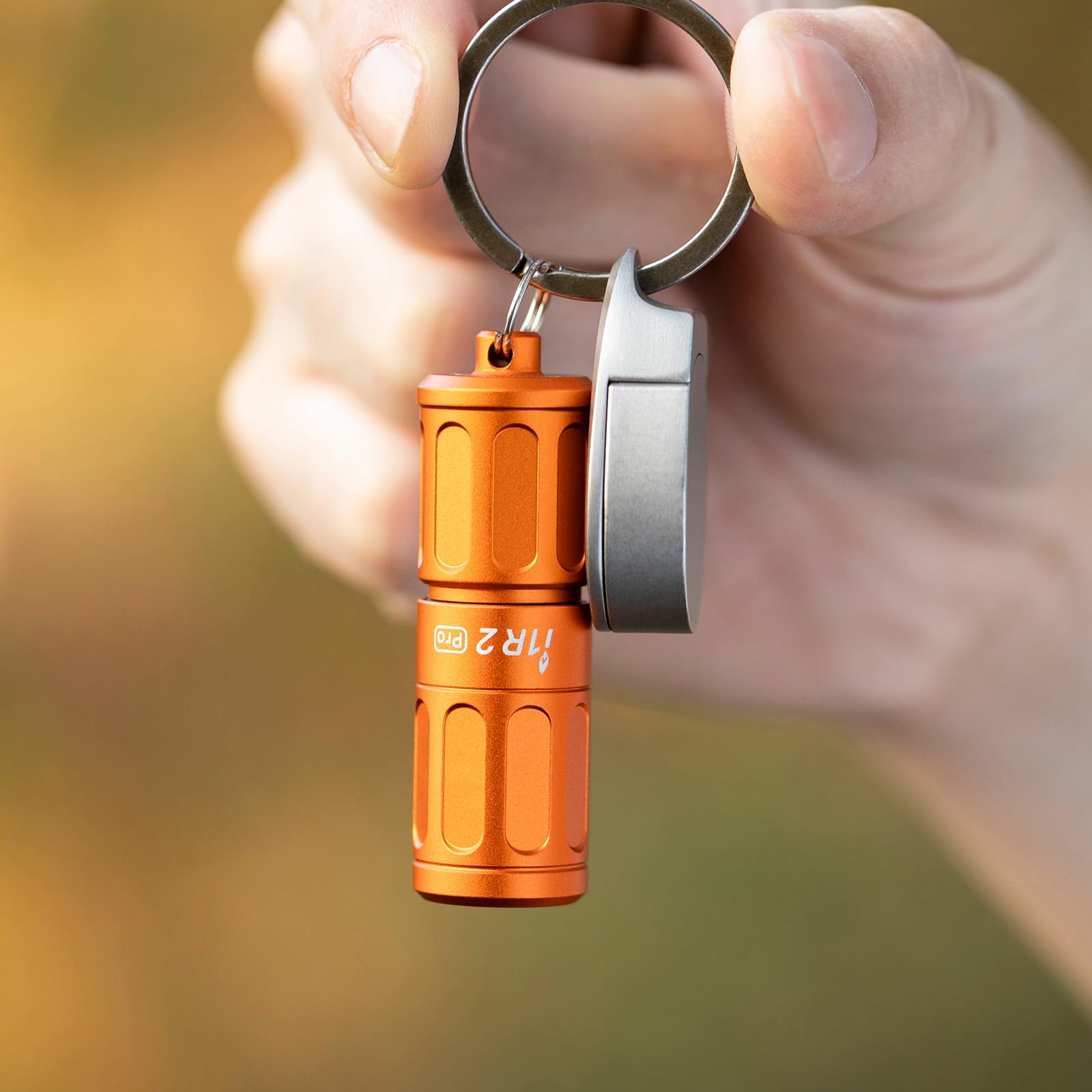 Olight i1R 2 Pro Capsule Orange twisted on in hand, showing one-handed operation