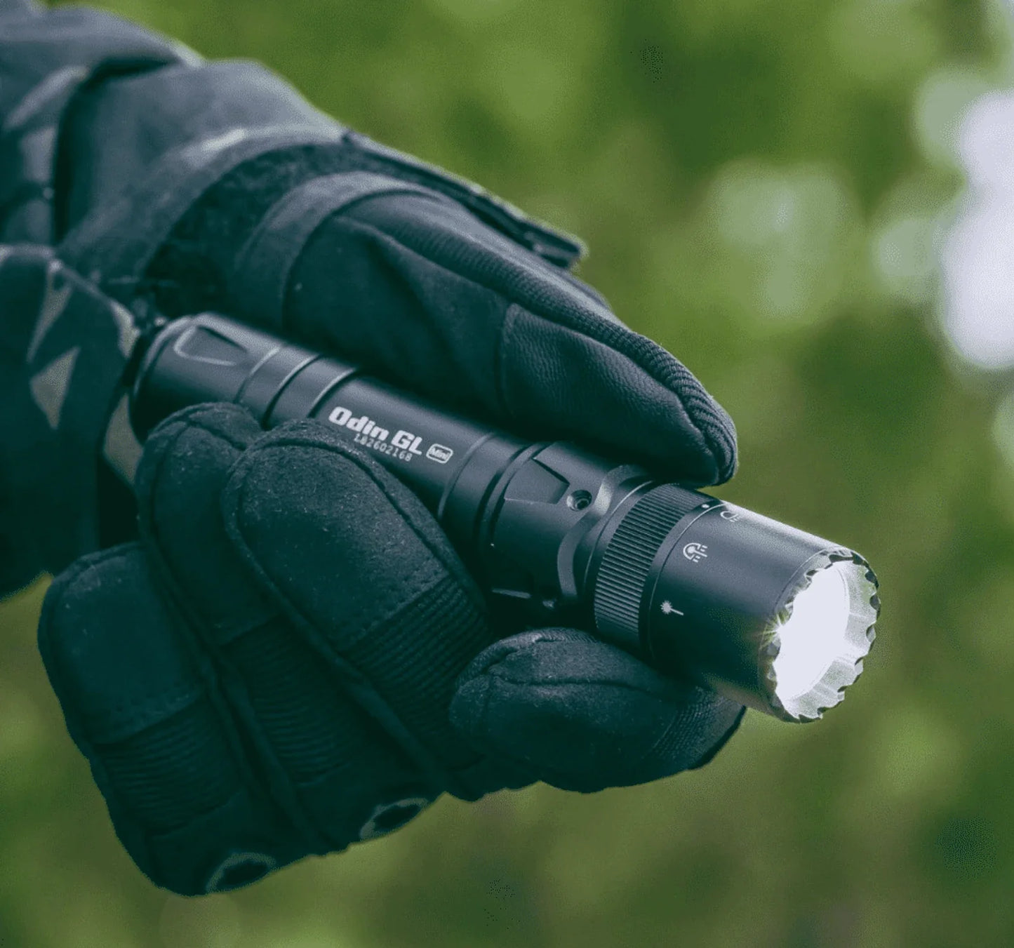 Olight Odin GL Mini held in a gloved hand showing its compact size