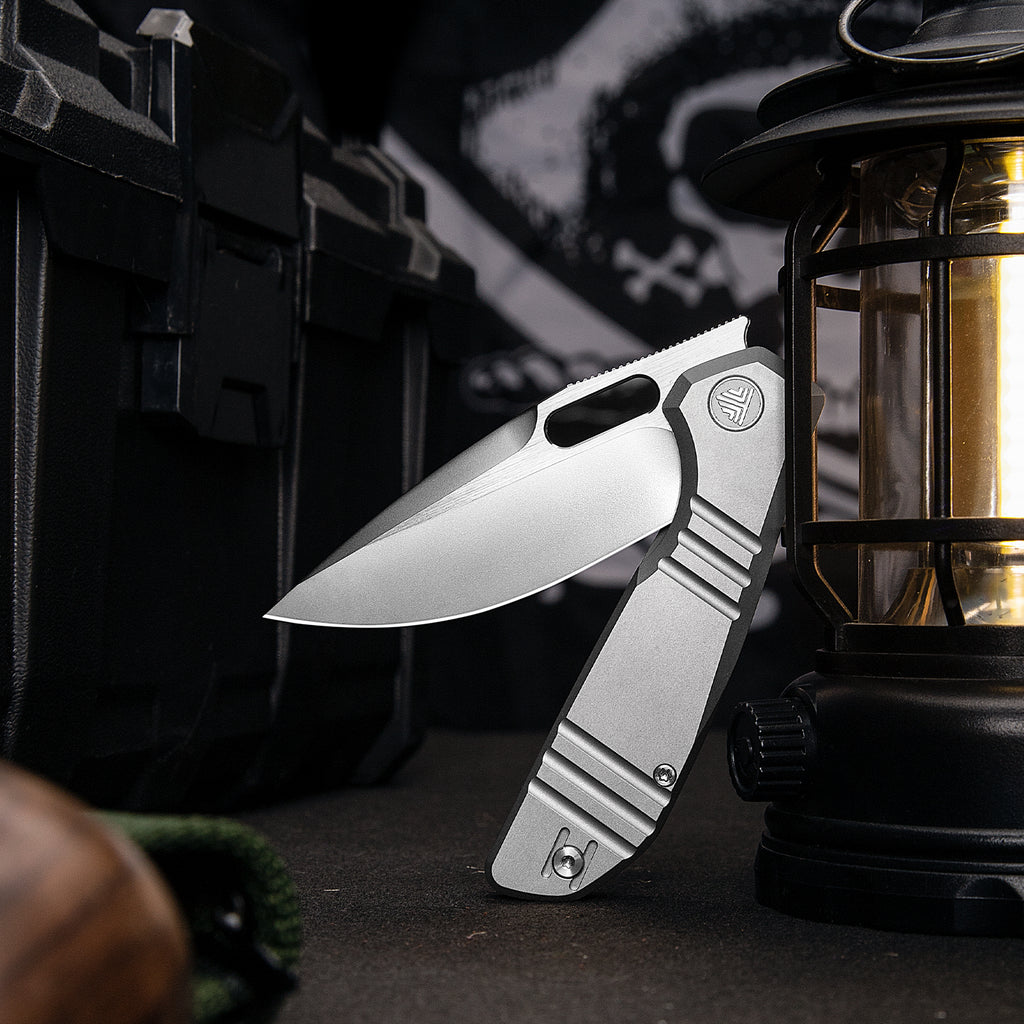 TRIVISA Gecko-P JM04-P-M 3.4" M390 drop point liner lock knife displayed with camping gear