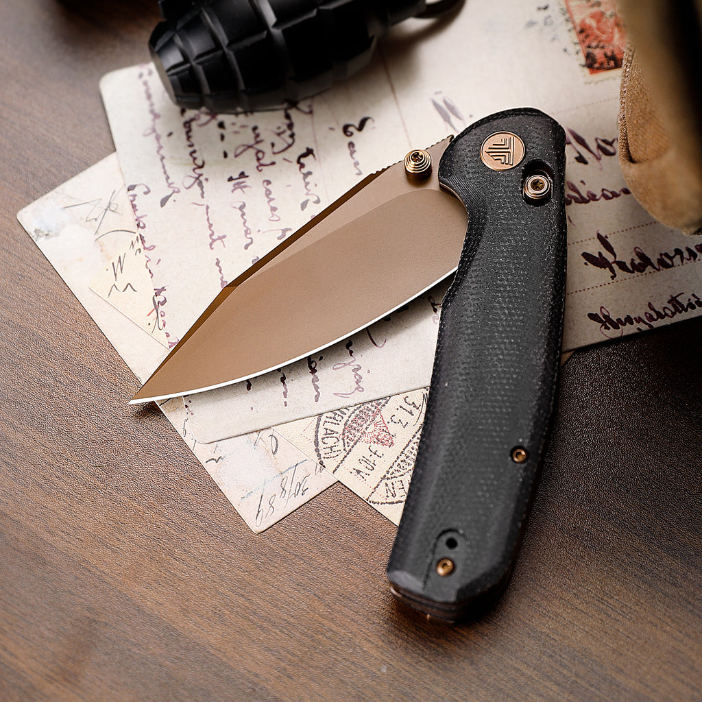 Black folding knife with drop point blade on vintage letter
